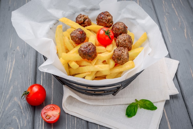 Boulettes de viande grillée avec frites sur table en bois