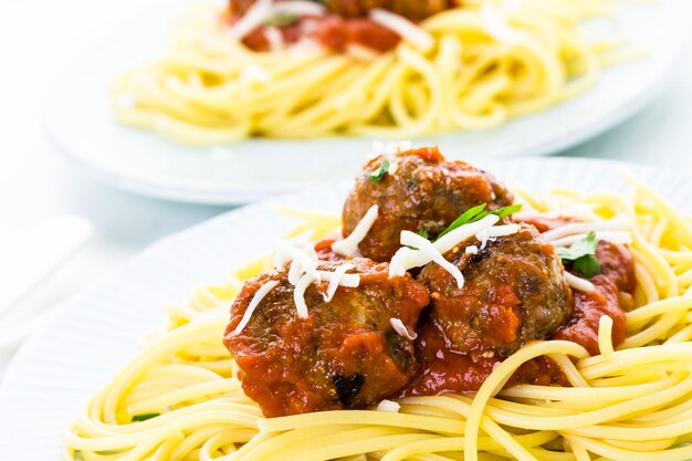 Boulettes de viande italiennes faites maison garnies de coriandre et de parmesan sur des spaghettis pour le dîner.