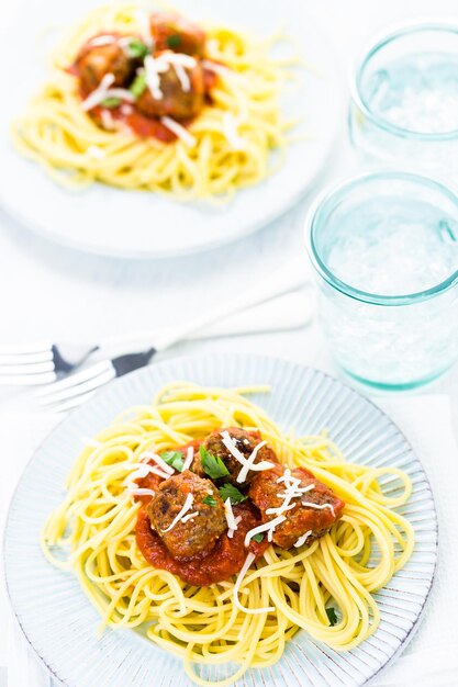 Boulettes de viande italiennes faites maison garnies de coriandre et de parmesan sur des spaghettis pour le dîner.