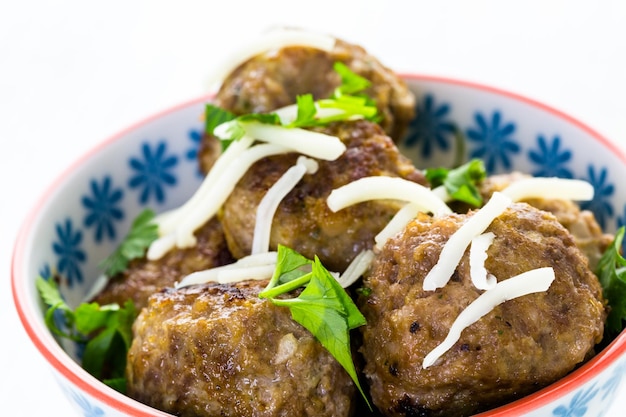 Boulettes de viande italiennes maison garnies de coriandre et de parmesan dans un petit bol.