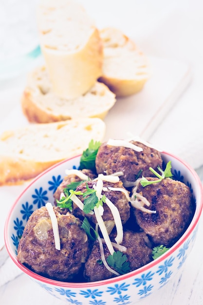 Boulettes de viande italiennes maison garnies de coriandre et de parmesan dans un petit bol.