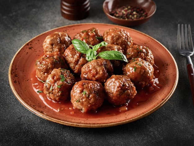 Boulettes de viande maison avec sauce tomate et épices servies dans une assiette sur fond gris