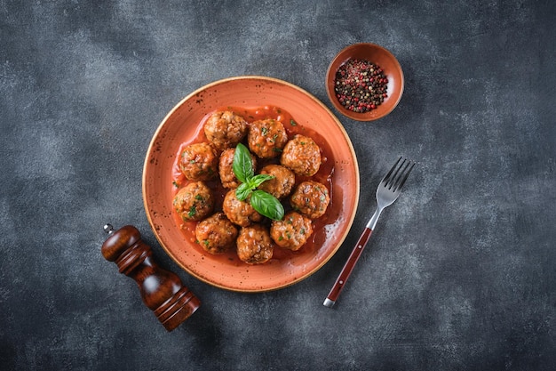 Boulettes de viande maison avec sauce tomate et épices servies dans une assiette sur fond gris