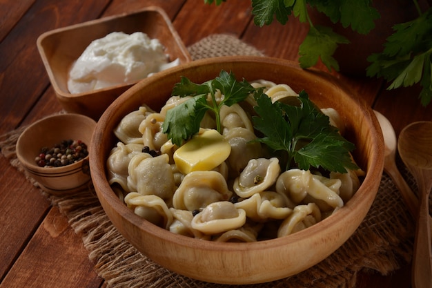 Boulettes de viande maison servies avec de la crème sure et du persil frais sur une assiette. Cuisine russe traditionnelle - pelmeni