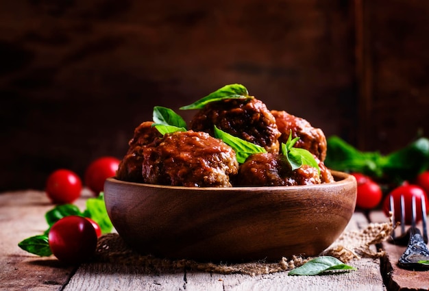 Boulettes de viande de porc et de boeuf avec sauce tomate épicée dans un bol vintage fond en bois mise au point sélective