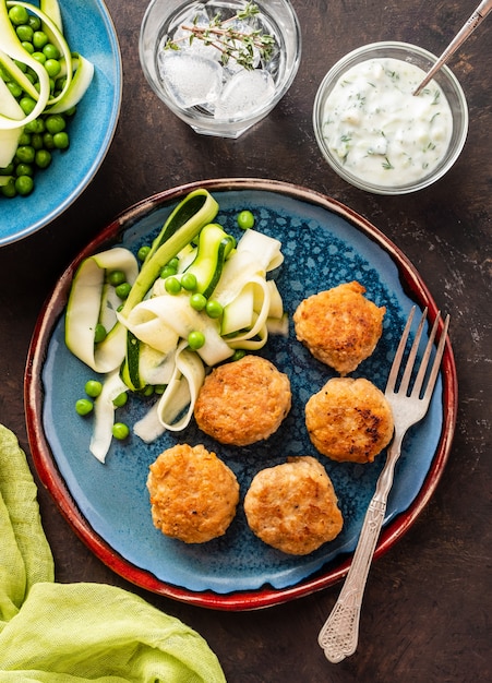 Boulettes de viande de poulet avec salade de courgettes et petits pois, sauce au yogourt à l'ail.