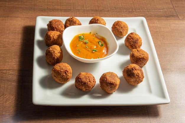 Boulettes de viande et sauce aux pois chiches végétaliens sur une assiette blanche sur une mise au point sélective en bois