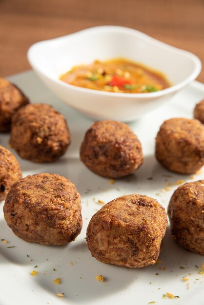 Boulettes de viande et sauce aux pois chiches végétaliens sur une assiette blanche sur une mise au point sélective en bois