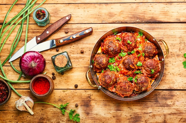 Boulettes de viande à la sauce tomate avec asperges sur table en bois