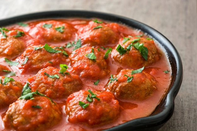 Boulettes de viande à la sauce tomate dans une poêle en fer sur une table en bois se bouchent