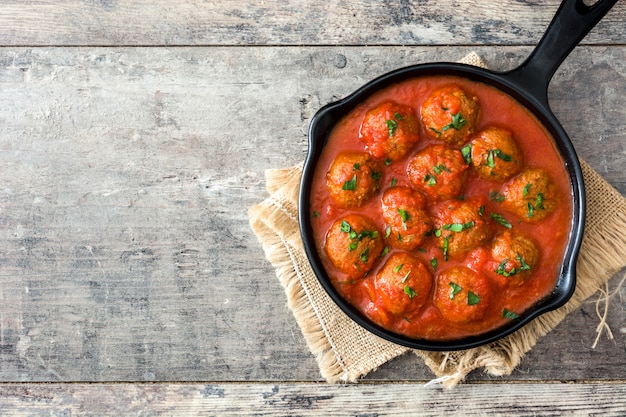 Boulettes de viande à la sauce tomate dans une poêle en fer sur une table en bois vue de dessus