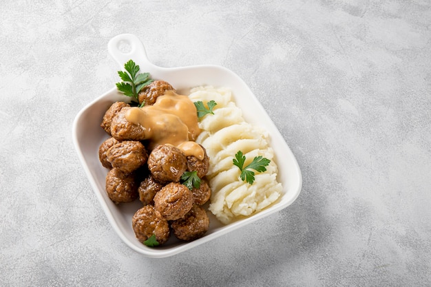 boulettes de viande suédoises traditionnelles avec sauce crémeuse et purée de pommes de terre sur fond gris vertical