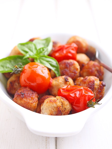 Boulettes de viande à la tomate dans un plat blanc sur fond blanc. mise au point sélective.