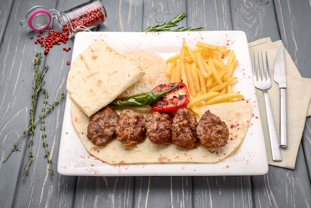 Boulettes de viande de veau grillées avec garniture de pommes de terre sur table en bois