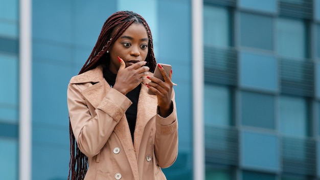 Bouleversé choqué jeune femme debout à l'extérieur recevant des e-mails sur téléphone portable lisant de mauvaises nouvelles tristes