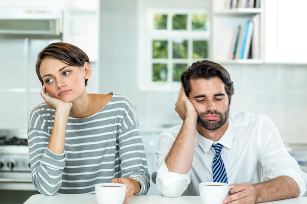 Bouleversé couple avec tasse de café assis à table