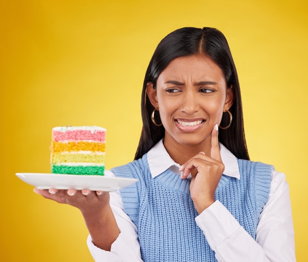 Bouleversé femme gâteau arc-en-ciel et studio tout en pensant à la catastrophe ou à l'erreur de célébration d'anniversaire