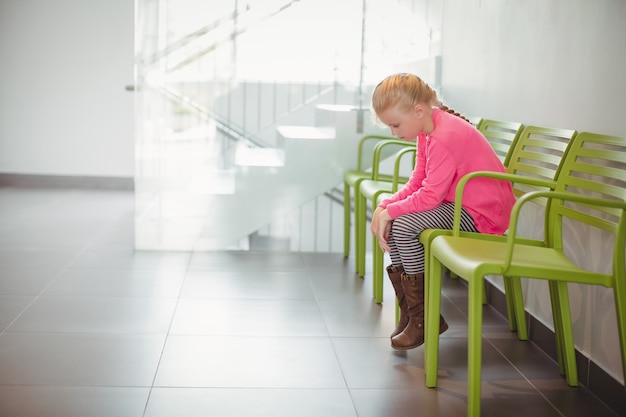 Bouleversé fille assise sur une chaise dans le couloir