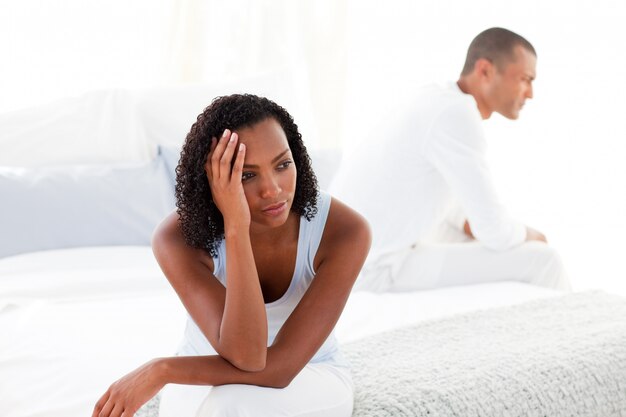 Bouleversé jeune couple assis sur le lit séparément