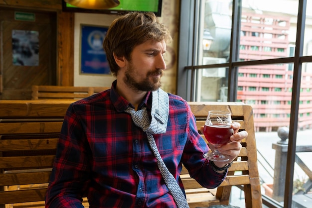 Bouleversé jeune homme buvant alcoolique assis à table dans un bar avec verre à boire de la bière seul