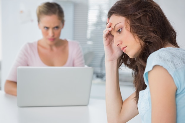 Bouleversée femme pensant tandis que son ami en colère la regarde fixement