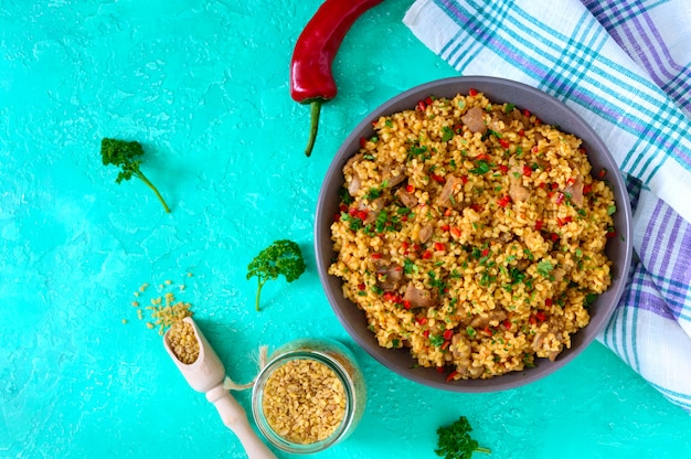 Boulgour au poulet et légumes. Délicieuse salade tiède et saine sur un fond clair. Pilaf de boulgour. Vue de dessus, pose à plat.