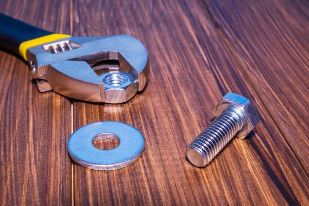 Boulon et écrou en métal sur fond en bois vintage avec clé à molette