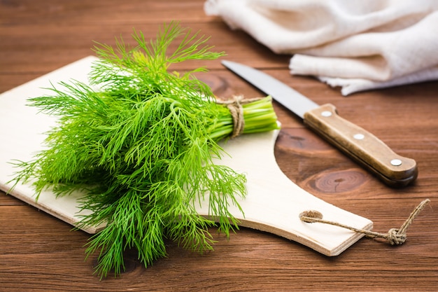 Bouquet d'aneth frais sur une planche à découper et un couteau sur la table