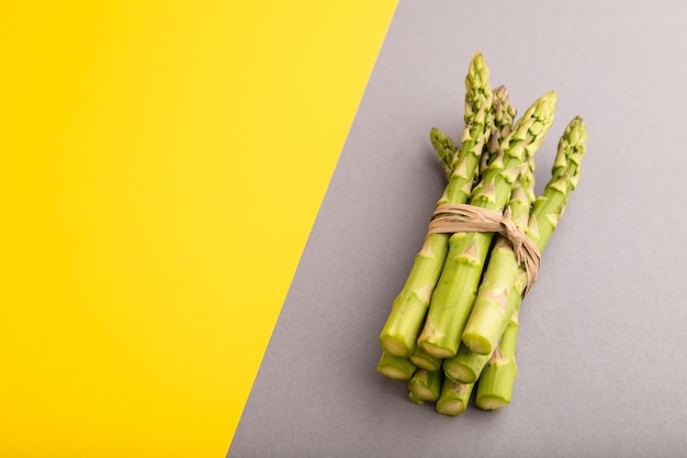 Bouquet d'asperges vertes fraîches sur fond pastel gris et jaune Espace de copie vue latérale