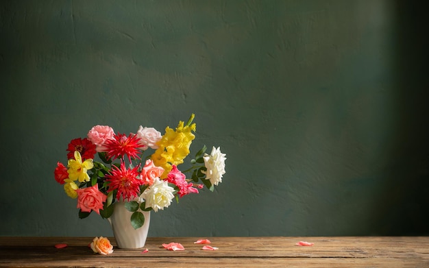 Bouquet d'automne avec des fleurs rouges et jaunes dans un vase blanc sur fond sombre