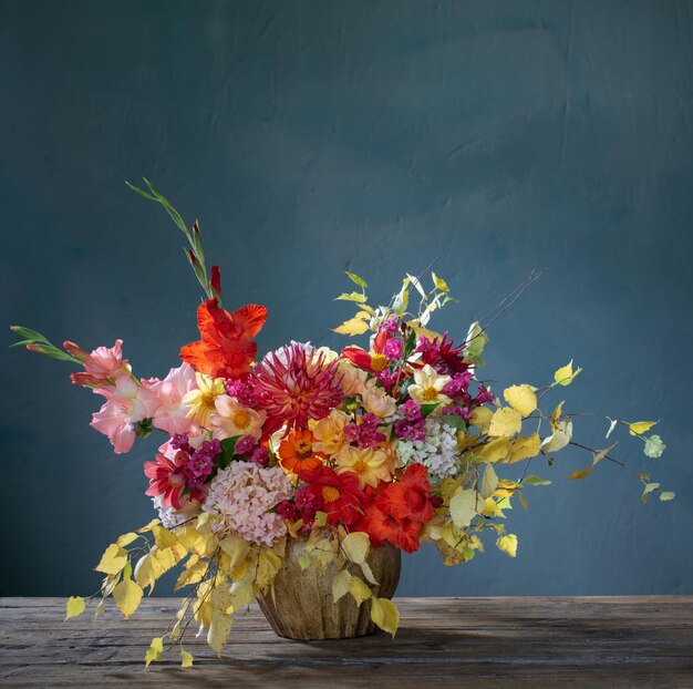 Bouquet d'automne avec des fleurs rouges et jaunes dans un vase en céramique sur fond sombre