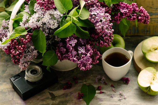 un bouquet de beaux lilas rose pourpre et une tasse de thé chaud