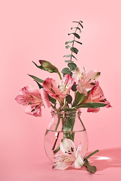 Bouquet de belles fleurs dans des bouteilles en verre sur fond rose Minimal Floral Festive Decoration copy space