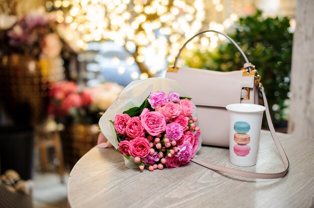 Bouquet de belles fleurs roses et élégant sac à main sur la table