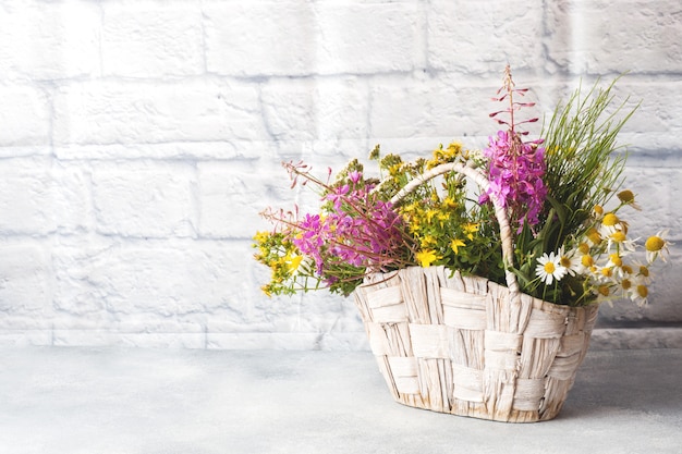 Bouquet de belles fleurs sauvages dans un panier sur fond gris avec espace de copie.