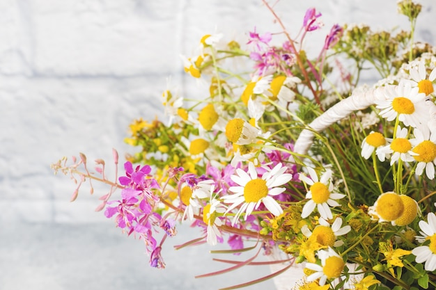 Bouquet de belles fleurs sauvages dans un panier sur une surface grise avec espace de copie.