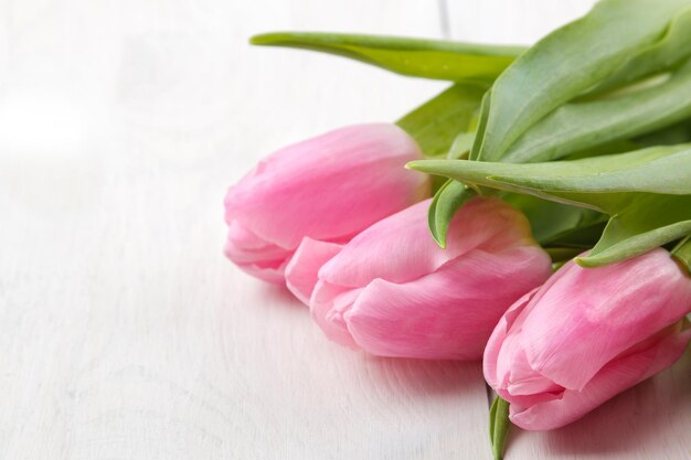 Un bouquet de belles fleurs de tulipes roses sur une table en bois blanc gros plan de vacances de printemps