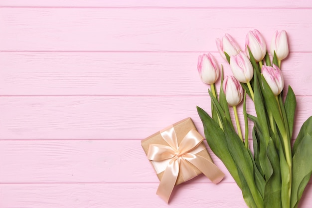 Un bouquet de belles tulipes et un cadeau sur une vue de dessus de fond en bois