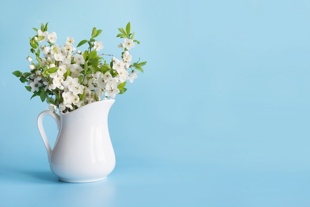 Bouquet de branche de cerisier en vase sur fond bleu.