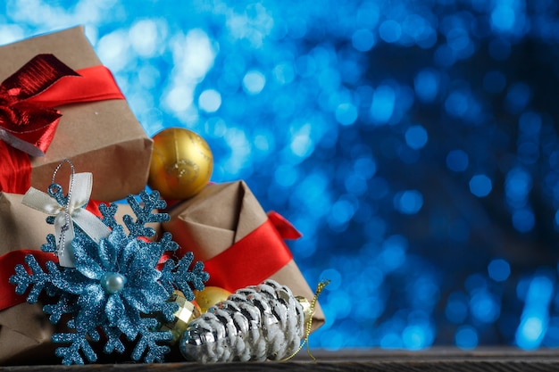 Bouquet de cadeaux de Noël et décoration de près. Boule d'or, pomme de pin en argent et flocon de neige brillant. Cadeau de réveillon du nouvel an emballé dans du papier avec un arc. Accessoire de vacances sur fond flou Tinsel