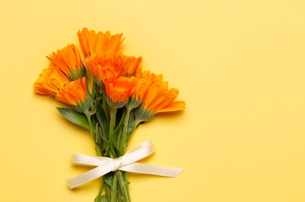 Un bouquet de calendulas orange sur fond jaune avec espace de copie.