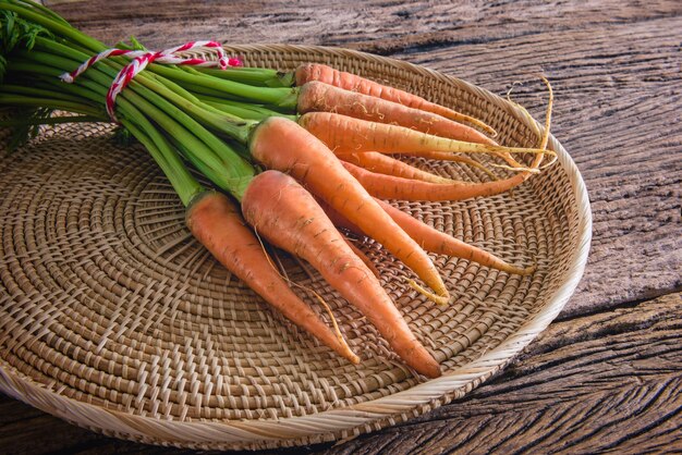 bouquet de carottes fraîches avec des feuilles vertes sur fond en bois