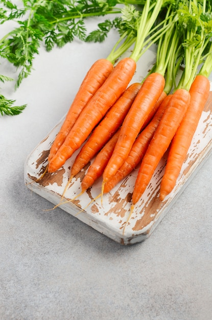 Bouquet de carottes fraîches sur une planche à découper en bois.