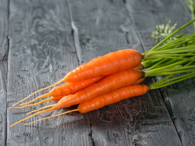 Bouquet de carottes mûres fraîches sur une table en bois foncé