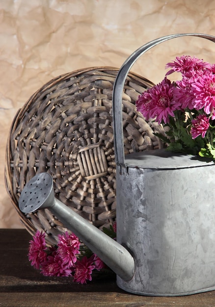 Bouquet de chrysanthème rose en arrosoir sur table en bois