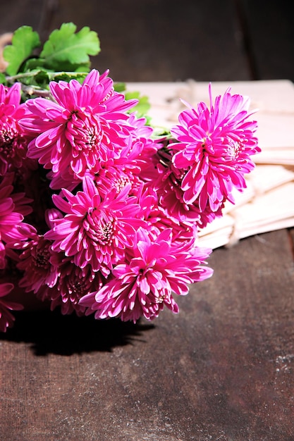 Bouquet de chrysanthème rose et lettres sur table en bois