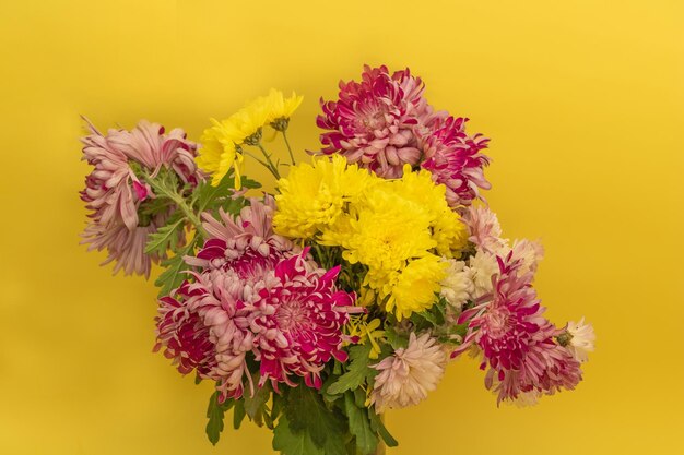 Un bouquet de chrysanthèmes rouges et jaunes sur fond jaune se bouchent