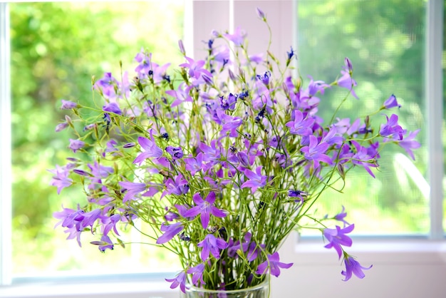 Bouquet de cloches violettes sur le rebord de la fenêtre en été