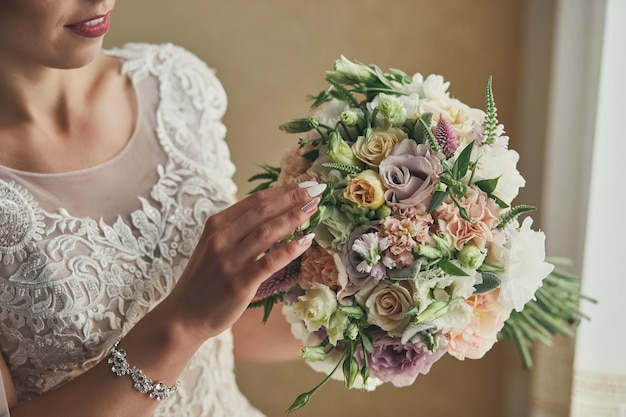 Bouquet dans les mains de la femme mariée se prépare avant la cérémonie de mariage