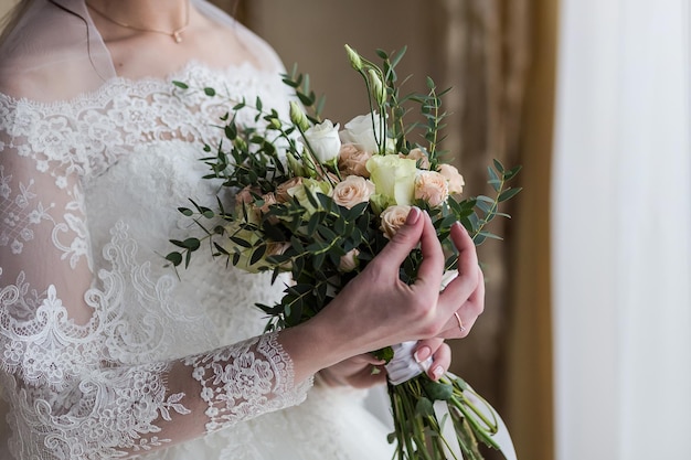 Bouquet dans les mains de la femme mariée se prépare avant la cérémonie de mariage